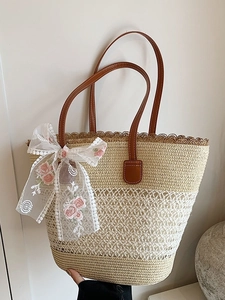 Straw tote bag with brown leather handles and white lace floral bow for beach holidays