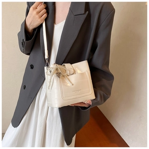 Borsa a secchiello beige con stampa coccodrillo, ciondoli di perle e modella in abito