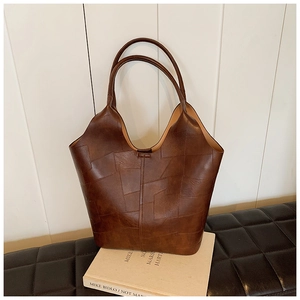 Détail du grand sac cabas marron vintage avec patchwork carré sur un livre blanc