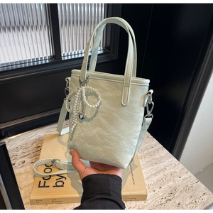 Detail of mint green bucket bag with ruched leather texture and pearl heart pendant