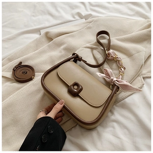 Detail of khaki crossbody bag with square buckle and silk scarf handle decoration