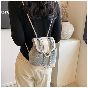 Detail of light blue sequined denim mini backpack with silver chain strap on model