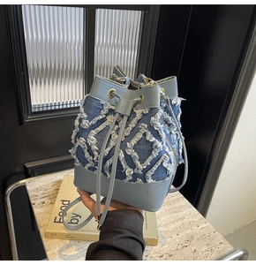 Detail of blue denim bucket bag with frayed quilted patterns and drawstring closure