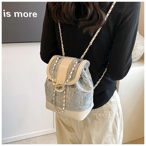Detail view of light blue sequined backpack with metal chain straps worn by a model