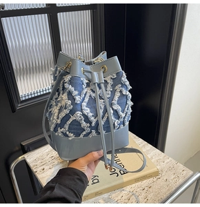 Detail of denim bucket bag with frayed quilted patterns and blue leather trim