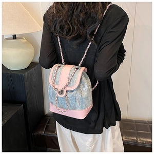 Detail of sequined denim bucket backpack with metal chain and drawstring closure on a model