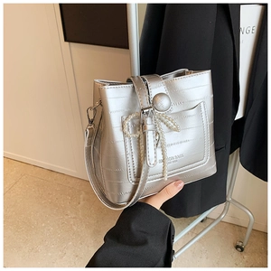 Dettaglio borsa a secchiello argento con texture coccodrillo e ciondolo a fiocco di perle