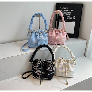 Detail of trendy drawstring bucket bags in four colors with wavy embroidery and woven handle