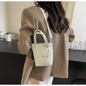 Pale green mini tote bag with pearl bow pendant and adjustable strap shown on model