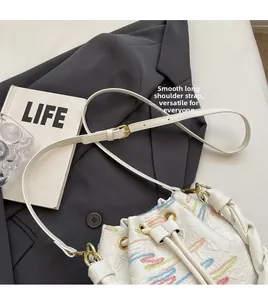 Detail of white bucket bag with colorful embroidery and adjustable leather strap