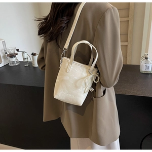 Detail of cream bucket bag with marble texture and pearl heart charm accessory