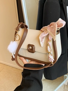 Elegant beige and brown leather shoulder bag with decorative scarf and plush keychain charm