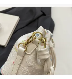 Close-up of white embossed leather bucket bag with rainbow stitching and gold hardware