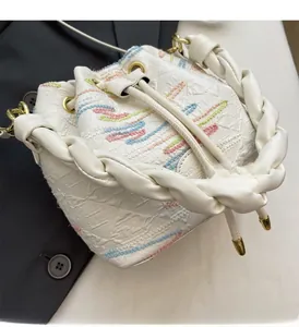 Close-up of a white bucket bag with colorful floral embroidery and a woven leather handle