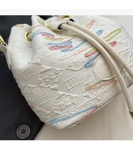 Close-up of white bucket bag featuring colorful embroidery and textured canvas details