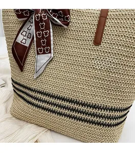 Detail of straw tote bag featuring brown leather handles and decorative bear print scarf