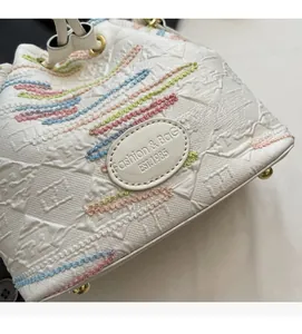 Detail shot of white bucket bag featuring embroidered FF monogram and fashion logo patch