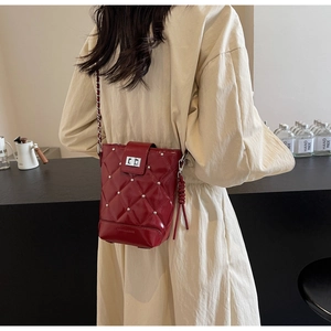 Detail der roten gesteppten Beuteltasche mit Nieten und Kettenriemen am Modell