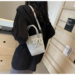 Gray pleated leather bucket bag featuring a pearl bow charm and adjustable strap