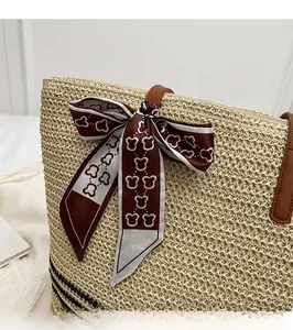 Detail of straw woven tote bag featuring a leather handle and cute bear print silk scarf