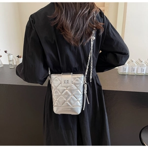 Detailansicht der silbernen gesteppten Beuteltasche mit Metallkette und Quasten-Dekor