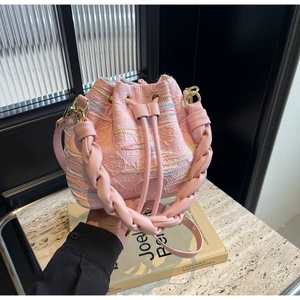 Detailed view of pink drawstring bucket bag with embossed textures and chic embroidery