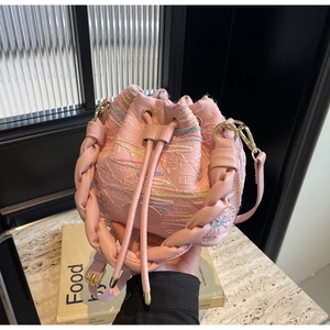 Detailed pink bucket bag with embossed texture and colorful woven accents