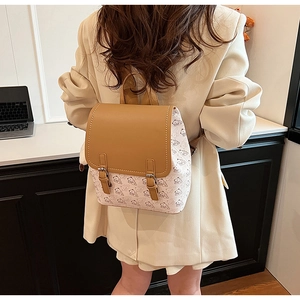 Détail d'un sac à dos chic crème avec motifs ours et rabat en cuir caramel