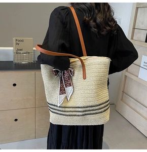 Détail d'un sac cabas en paille avec bandoulière en cuir et foulard en soie dans un décor bohème