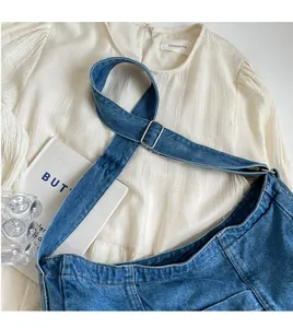 Detail of blue denim crossbody bag with adjustable strap and contrast stitching