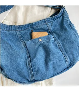 Detail of durable front pocket on blue denim tote bag with metal buckle closure