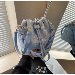 Close-up of light blue canvas bucket bag with floral embroidery and braided handle
