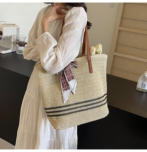 Detail of hand-woven straw tote with black stripes and brown leather straps