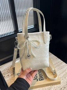 White textured leather bucket bag with large pearl bow charm and silver heart pendant