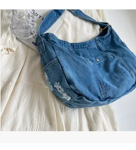 Detail of blue denim shoulder bag showing distressed edges and silver snap button pocket