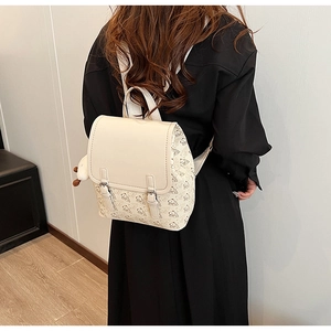 Détail d'un sac à dos crème avec motifs d'ours et peluche porté sur le dos