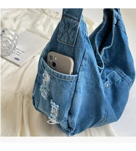 Close-up of denim tote bag side pocket with frayed edges holding a smartphone