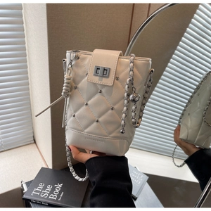 Detail der weißen gesteppten Beuteltasche mit Nieten und Metallkette auf spiegelnder Fläche