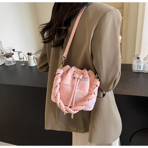 Detail of pink drawstring bucket bag with quilted texture and braided handle for women