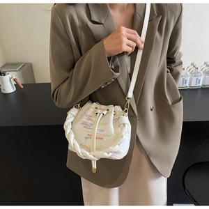 Detailed macro view of white bucket bag with colorful embroidery and woven handle