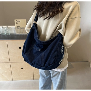 Detail of vintage denim tote bag showing distressed frayed edges and a front pocket