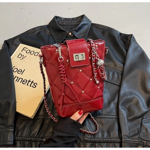 Detail der roten gesteppten Beuteltasche mit Kettenriemen und Metallnieten auf Leder