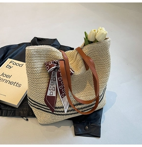 Détail du sac cabas en paille tressée avec anses en cuir marron et foulard en soie décoratif