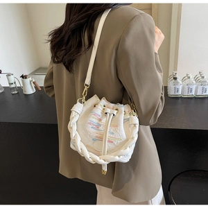 Close-up of a white bucket bag with colorful mosaic weave texture and woven handles