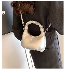 Detail of silver half-moon bag featuring pleated cloud handle and matte metallic leather