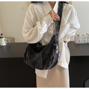 Detailed close-up of washed black denim crossbody bag featuring raw frayed edge design