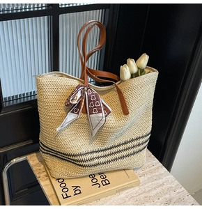 Détail du sac cabas en paille avec rayures noires, anses en cuir et foulard décoratif