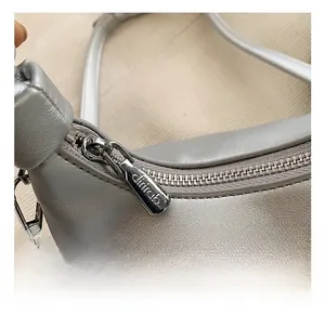 Close-up of metallic zipper and premium leather texture on a stylish silver-grey handbag