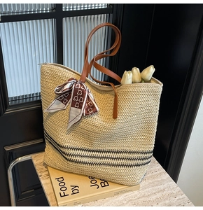 Detail of straw tote bag with black stripes, leather handles and decorative silk scarf