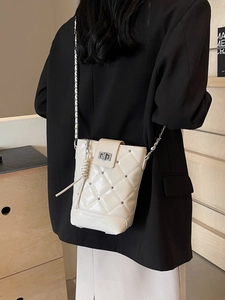 Beige Stepp-Umhängetasche mit Kettenriemen am Model in einem minimalistischen Raum